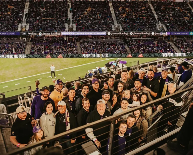 Group of fans posing at a crowded soccer stadium